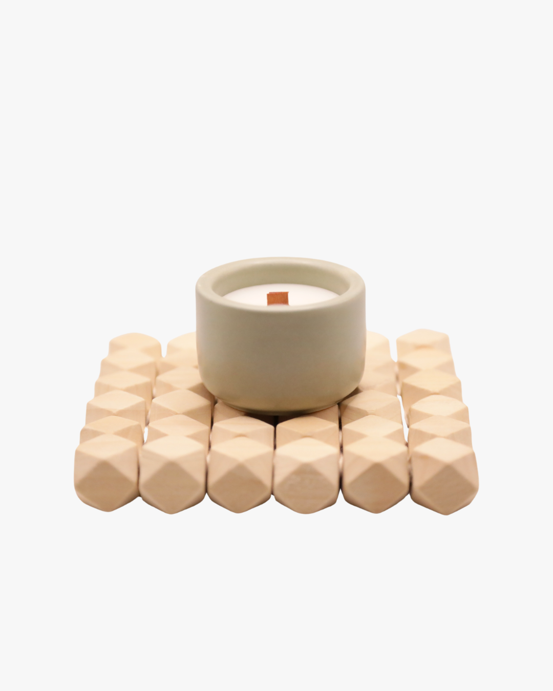 Mini bougie parfumée Nicaise en pot vert sauge avec mèche en bois, posée sur un support en bois, sur fond blanc.