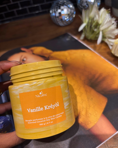 Bougie parfumée Nicaise Vanille Kréyòl en pot orange marbré, sur un magazine.