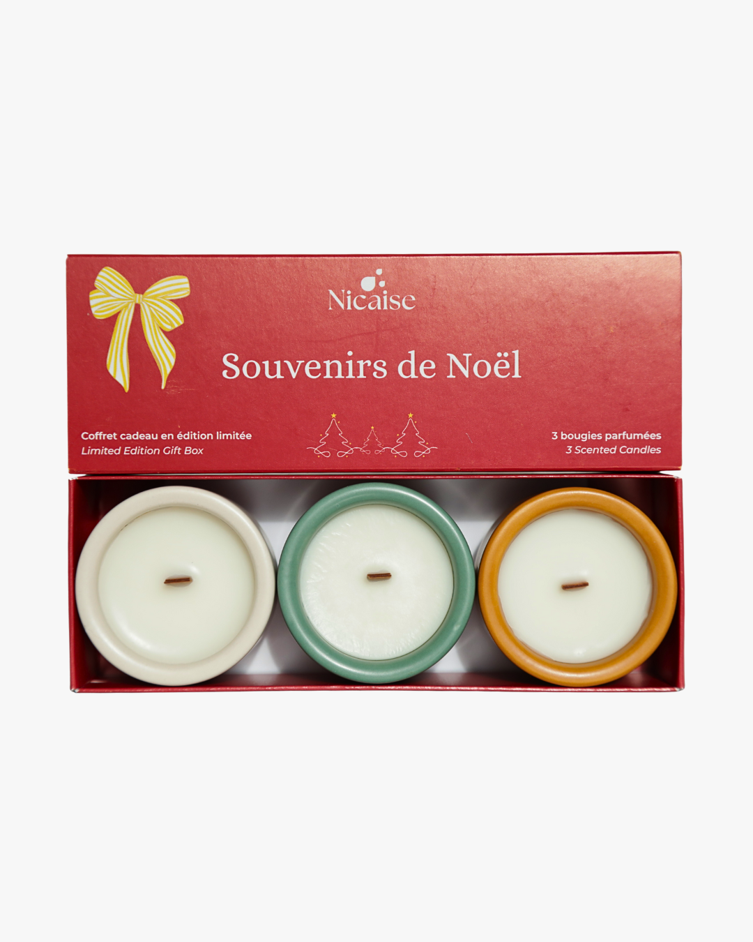 Coffret cadeau Nicaise « Souvenirs de Noël » ouvert avec 3 mini bougies parfumées en pots (blanc, vert, cuivré) et mèches en bois, sur fond blanc.