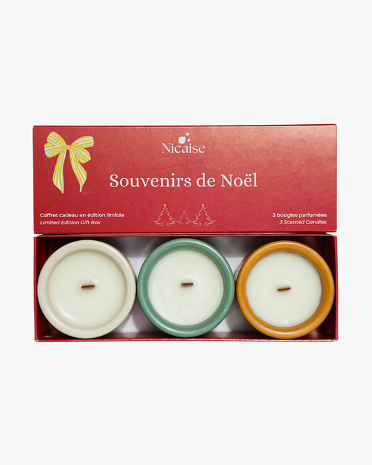 Coffret cadeau Nicaise « Souvenirs de Noël » ouvert avec 3 mini bougies parfumées en pots (blanc, vert, cuivré) et mèches en bois, sur fond blanc.