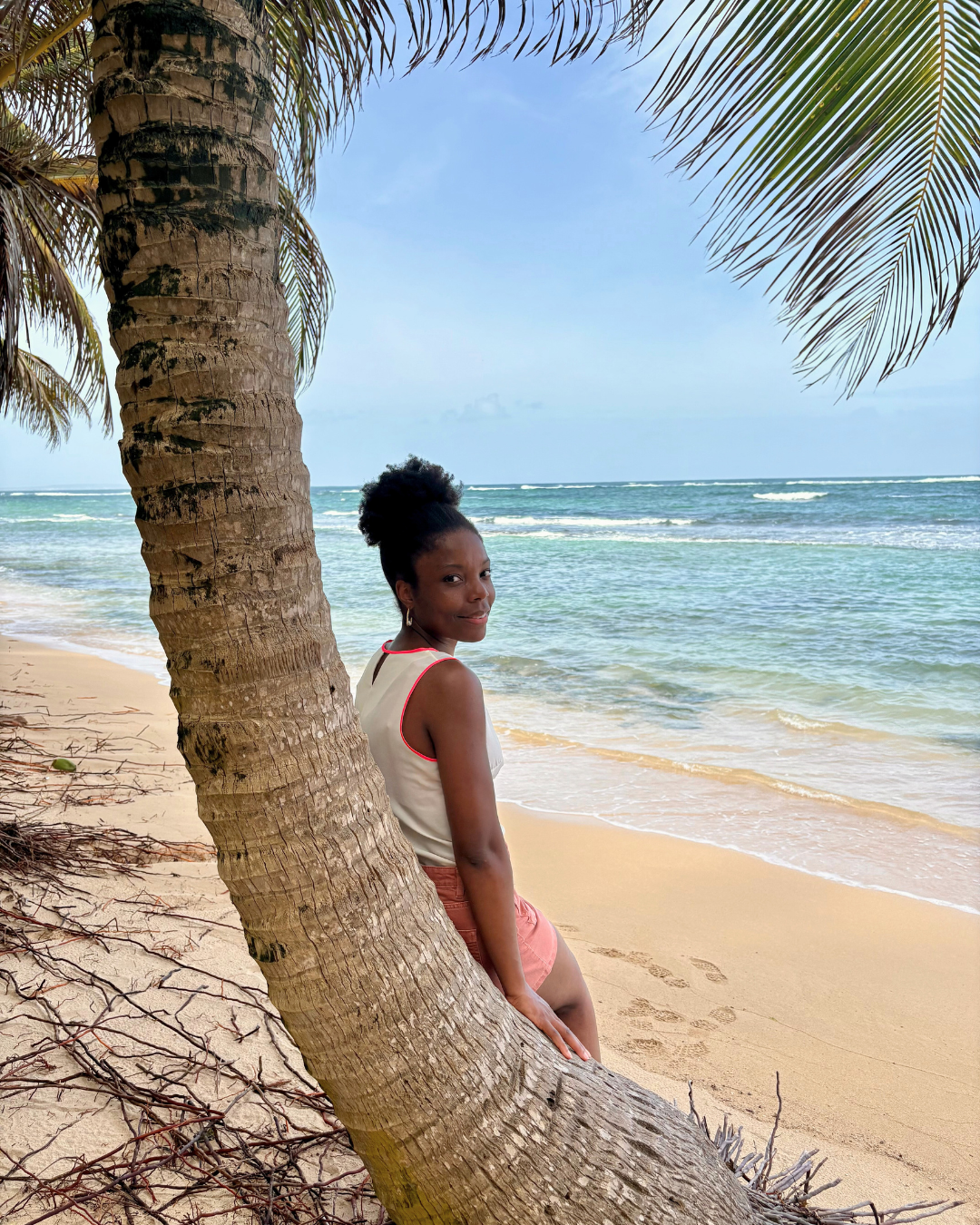 La fondatrice de Nicaise sur la plage en Guadeloupe, palmiers et cocotiers, mer turquoise, sable blanc fin.