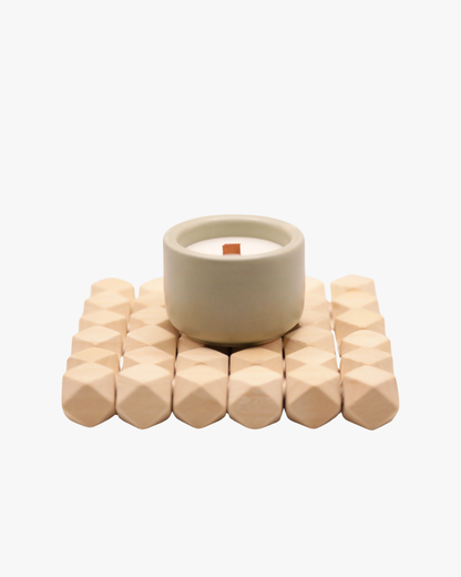 Mini bougie parfumée Nicaise en pot vert sauge avec mèche en bois, posée sur un support en bois, sur fond blanc.