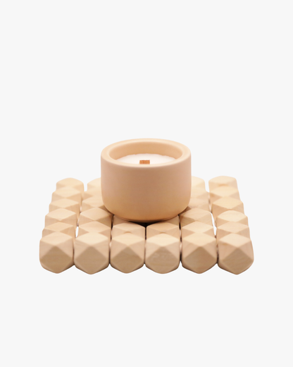 Mini bougie parfumée Nicaise « Vanille Kréyòl » en pot beige avec mèche en bois, posée sur un support en bois, sur fond blanc.